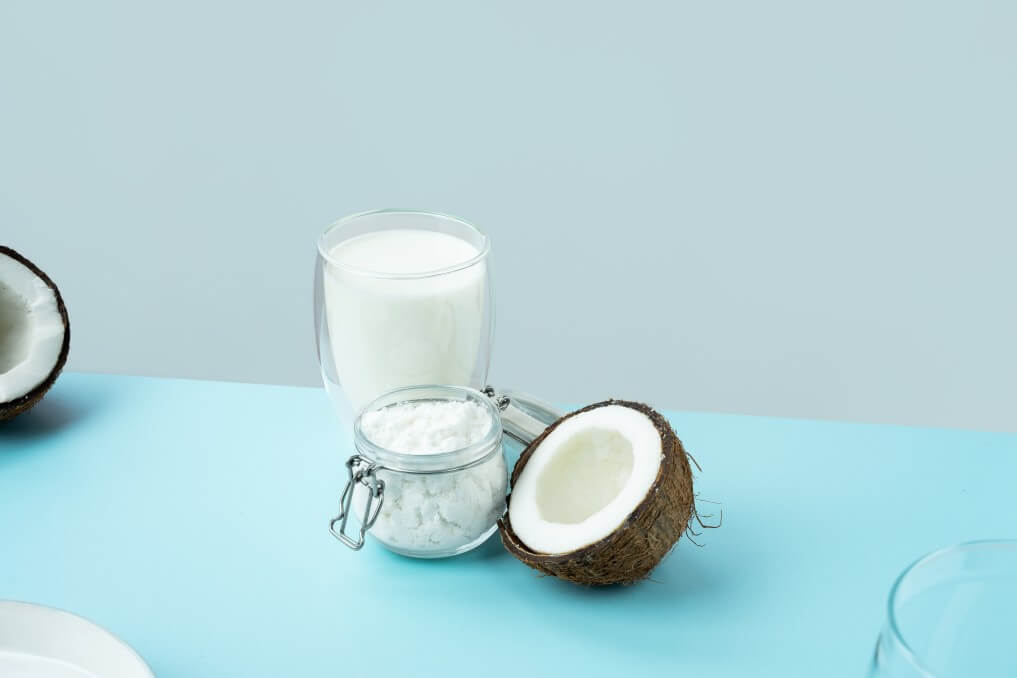 coconut milk with raw coconut on table with blue tablecloth