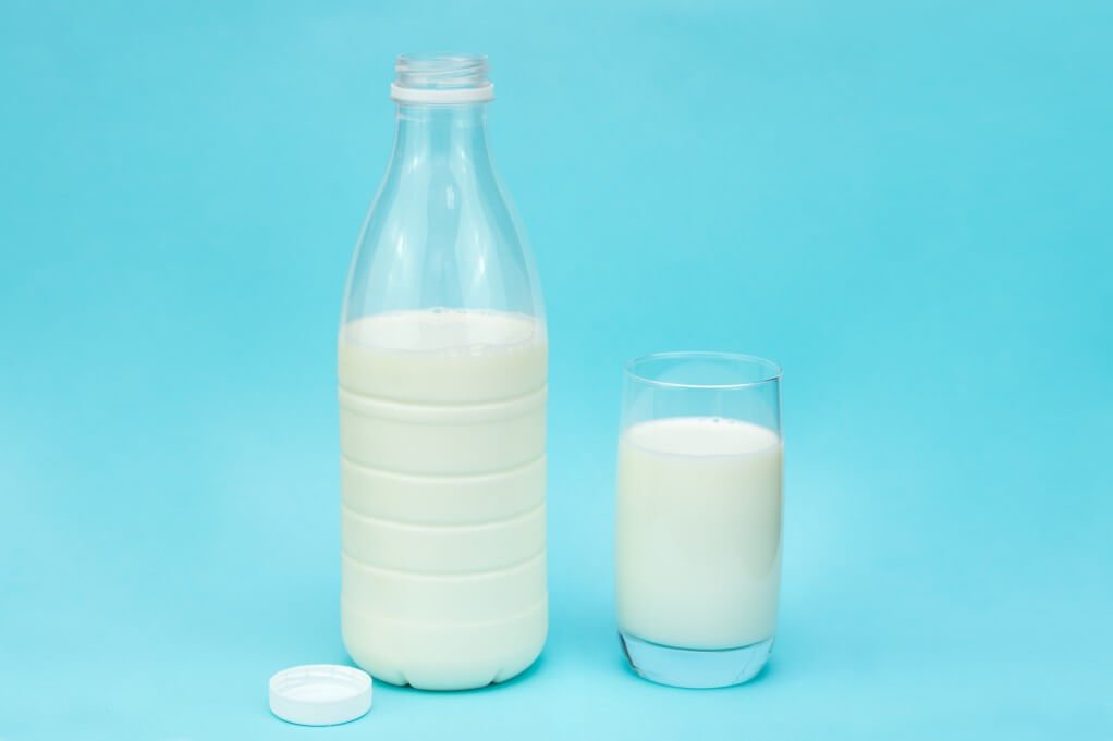 bottle and glass of milk on blue background