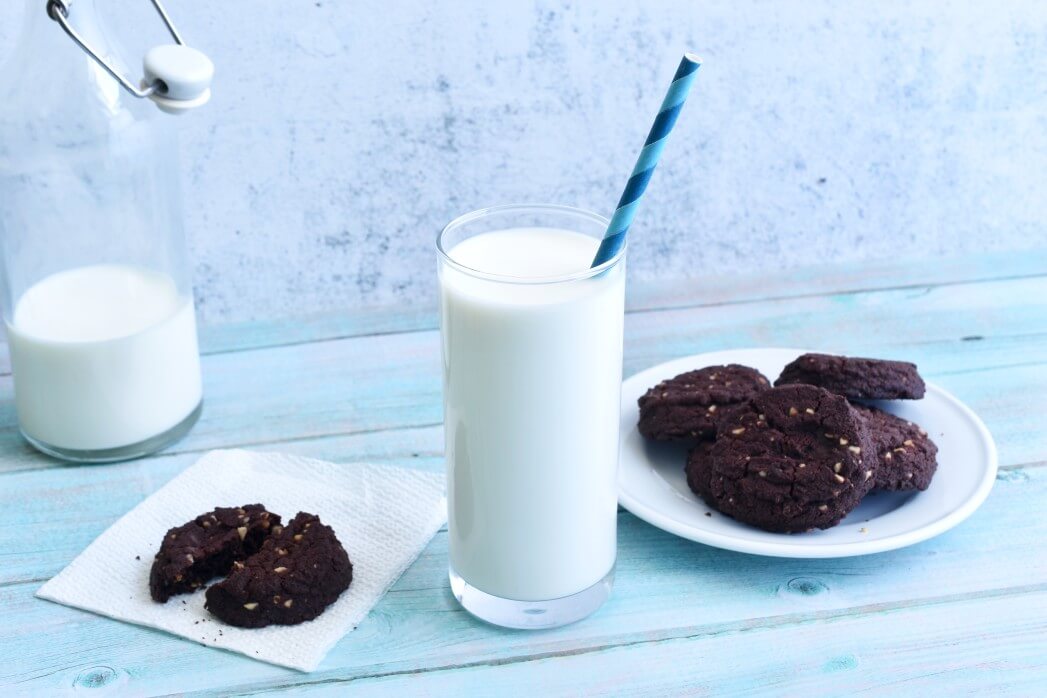 glass of milk with straw and cookies on plate