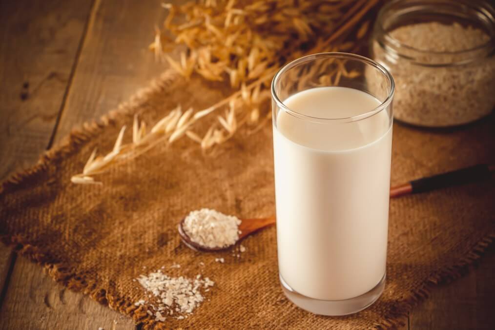 glass of oat milk on a wooden background