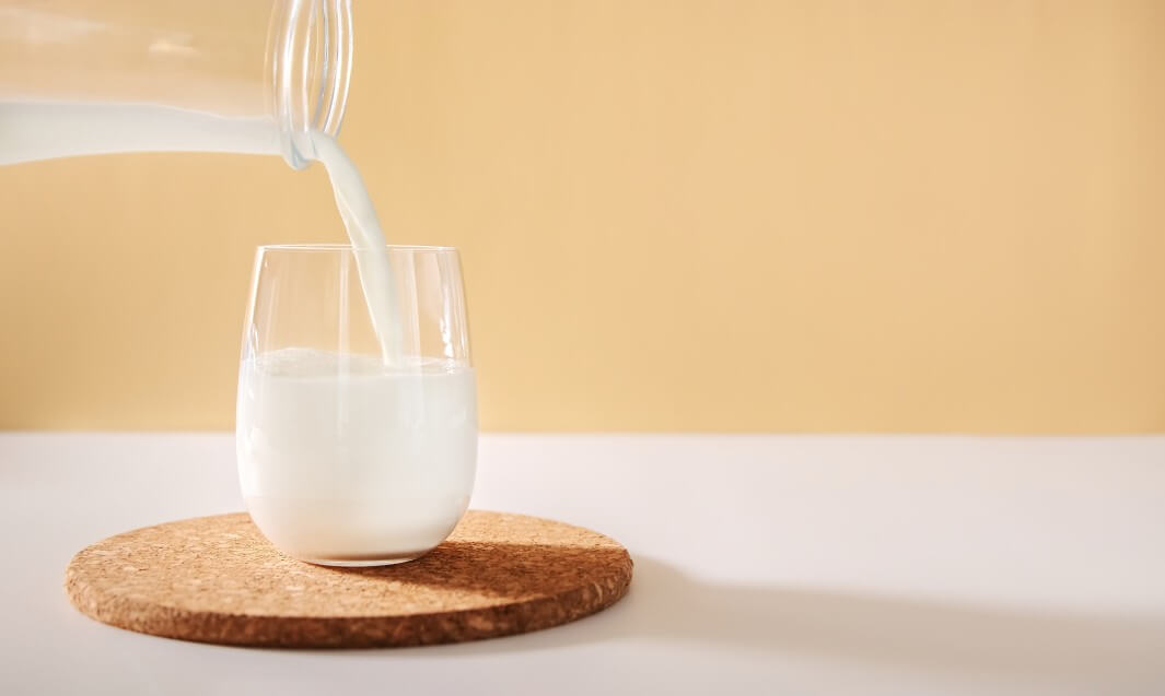 pouring almond milk into glass on trivet