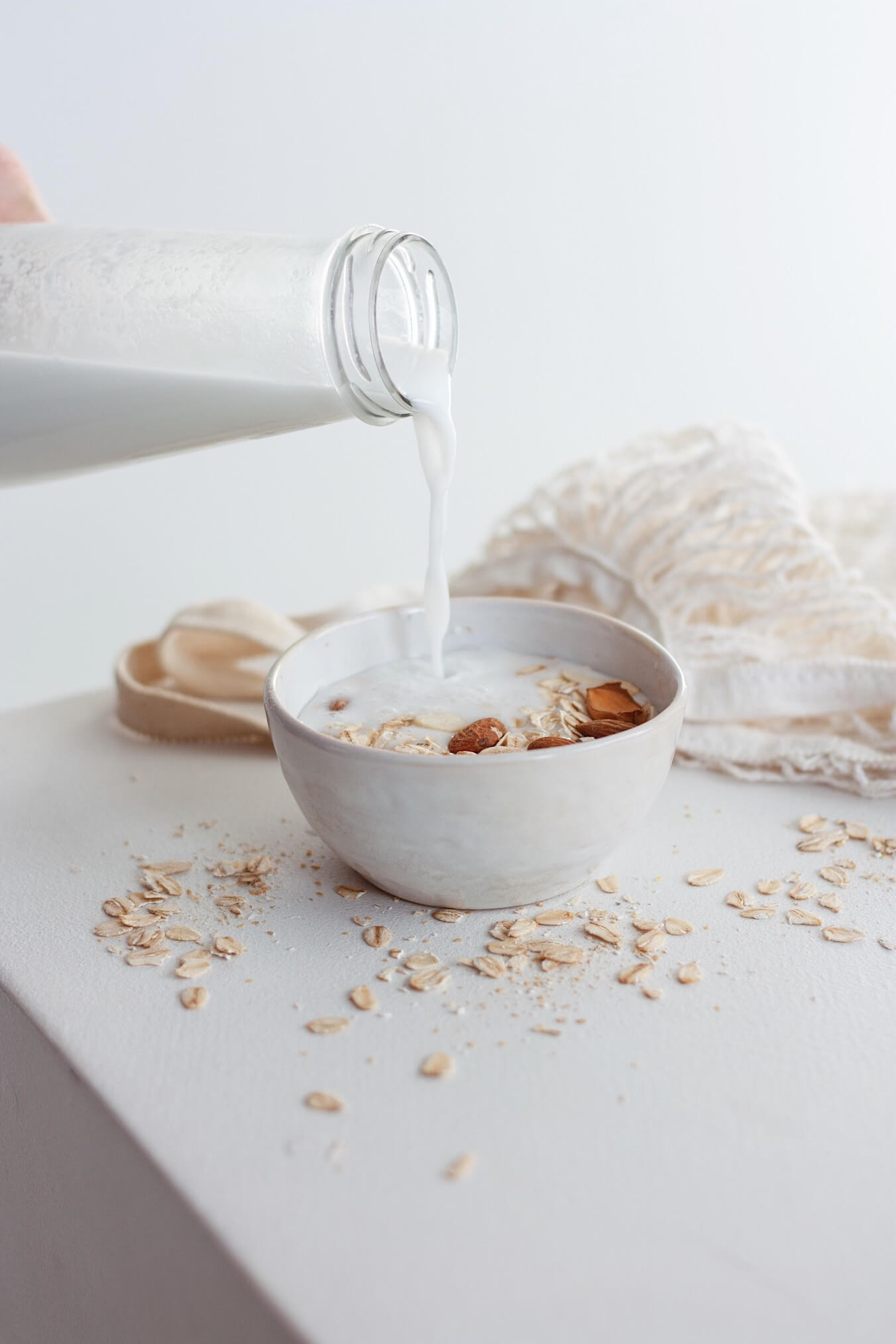 pouring milk into bowl of breakfast oats on table
