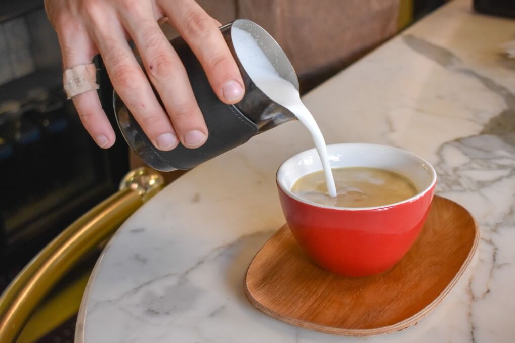 pouring milk into latte cup for frothing