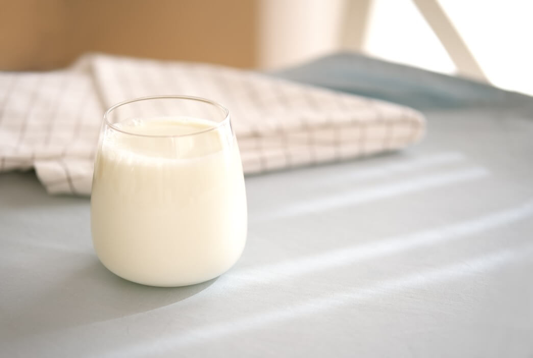 small glass of milk on table with dish cloth in background