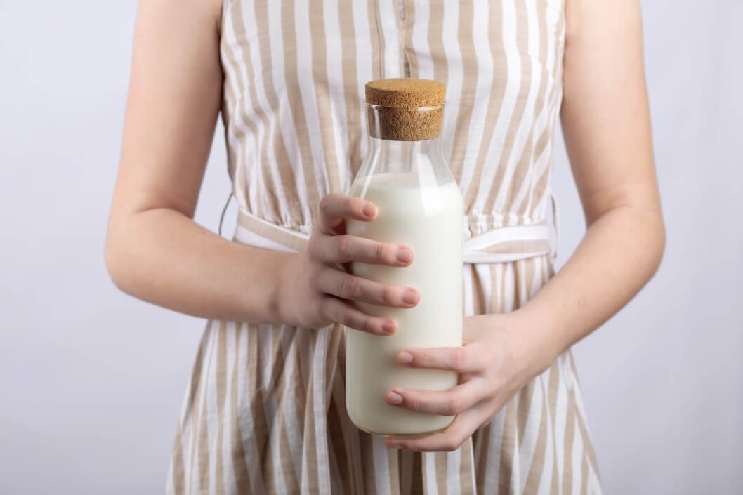 woman in dress holding glass bottle of milk