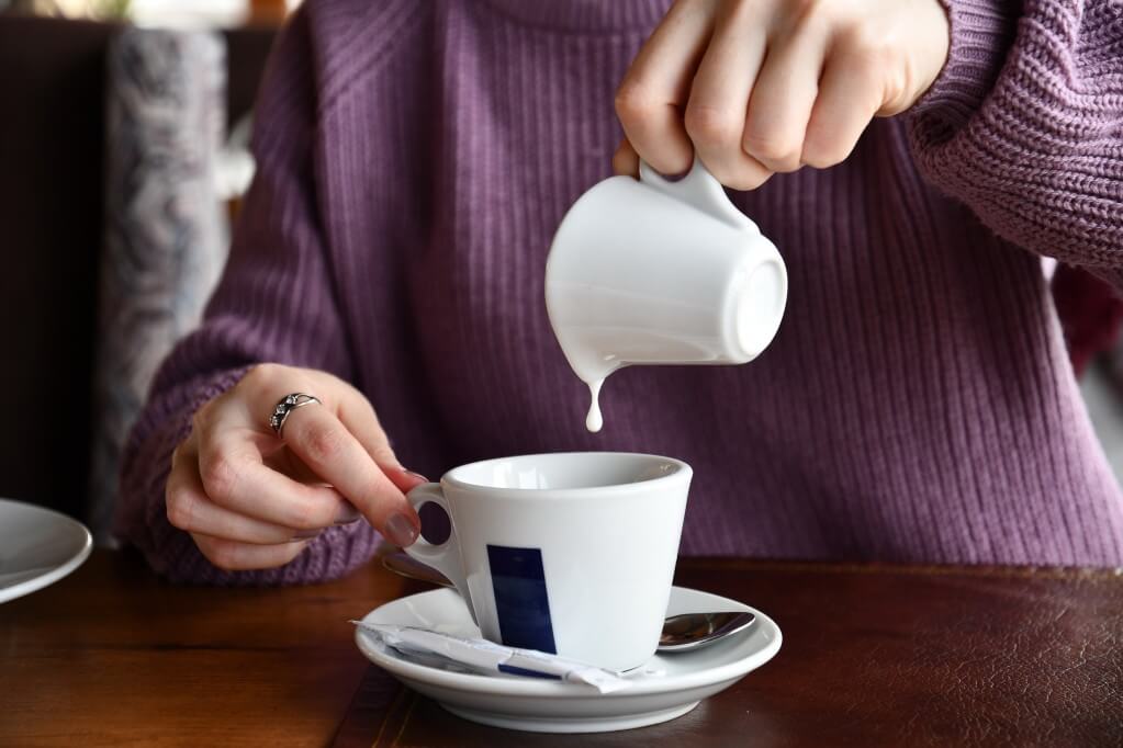 woman pouring oat milk into mug