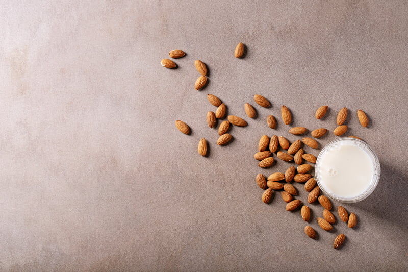 almond milk with scattered almonds on counter