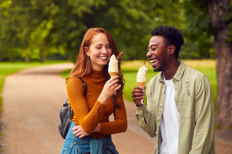 black mand white woman eating ice cream cones in park