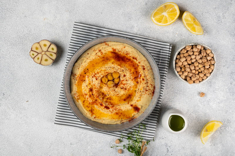 bowl of hummus with olive oil on tablecloth