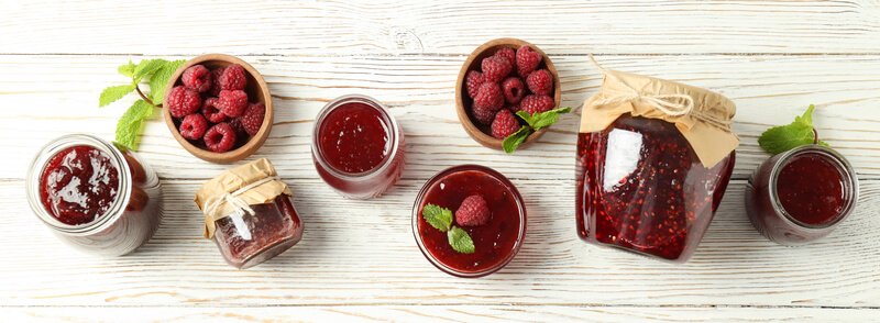 eight jars of raspberry jam on wooden table