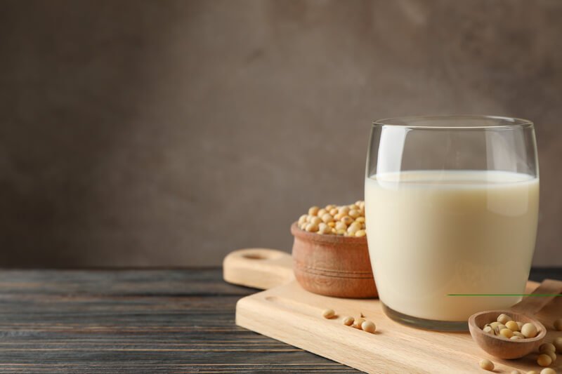 glass of soy milk and soybean seeds on wood board