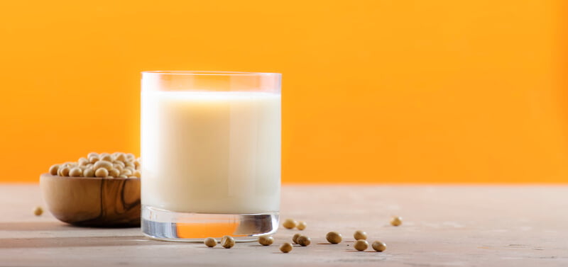 glass of soy milk on table with orange background
