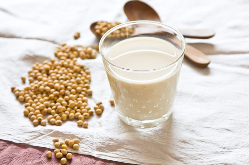 glass of soy milk with soy bean seeds on cloth