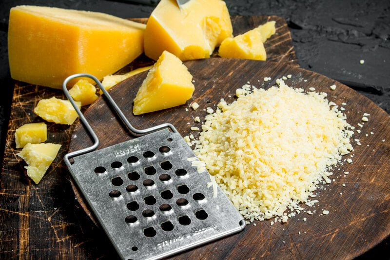 grated cheese on wooden block with cheese blocks in background