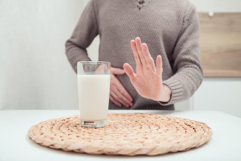 man holding stomach and raising hand drinking expired spoiled milk