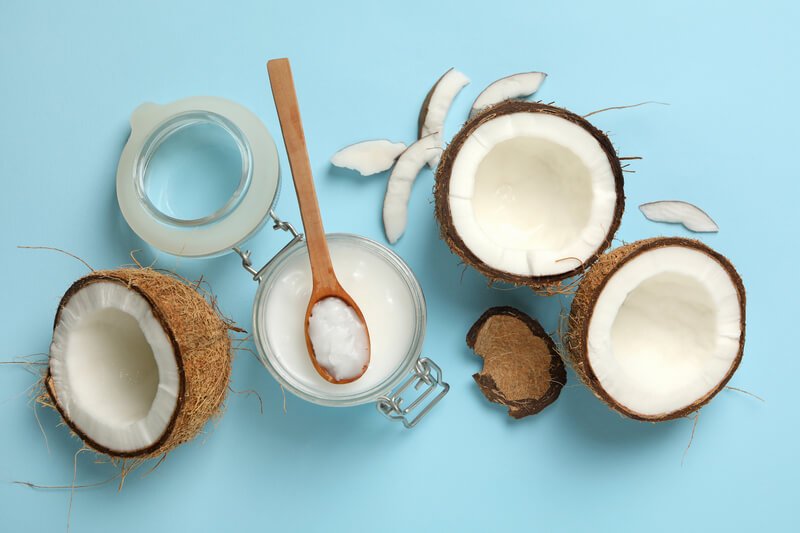 open coconut and coconut milk on light blue background