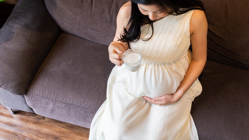 pregnant woman in white dress with glass of milk