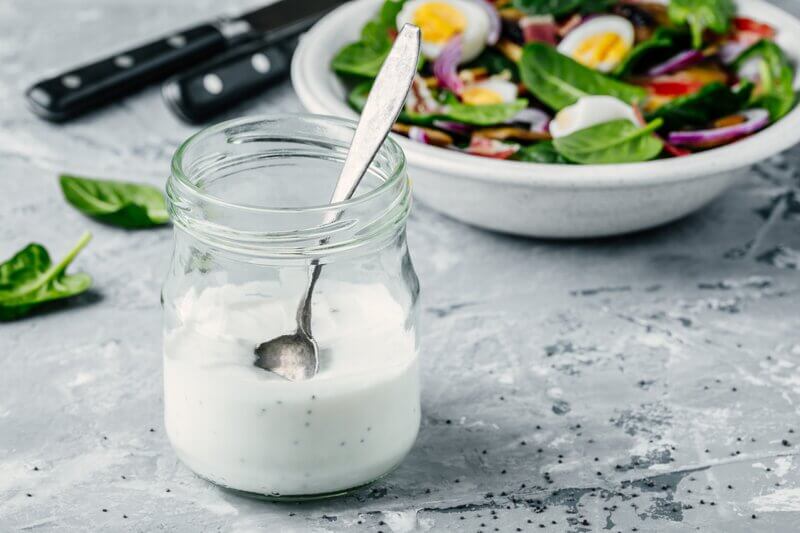ranch dressing in glass jar with salad in background