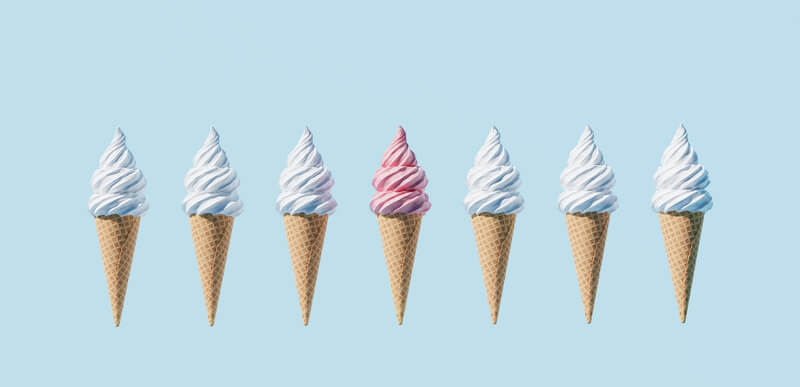 seven soft serve ice cream cones on light blue background
