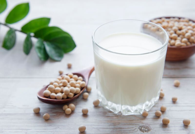 short glass of soy milk on table with soy beans