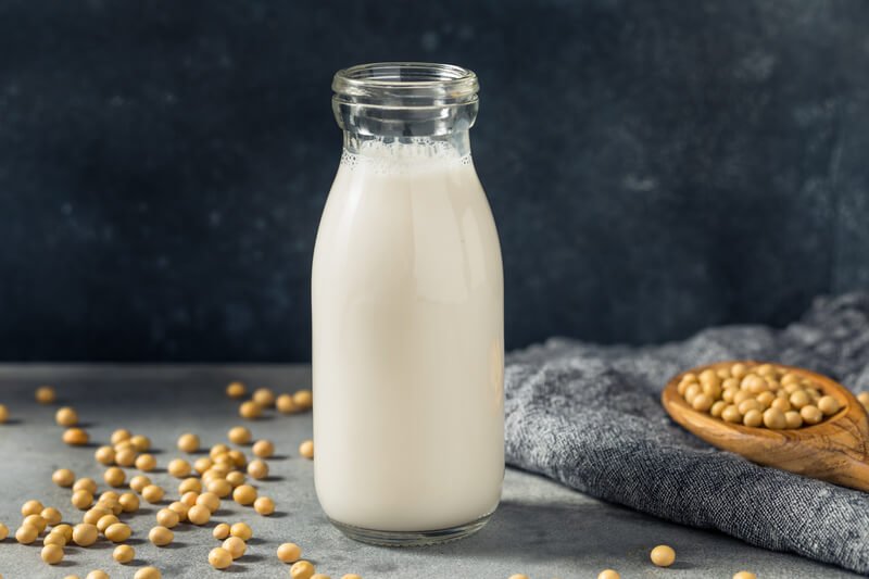 soy milk in glass bottle on counter with dark background