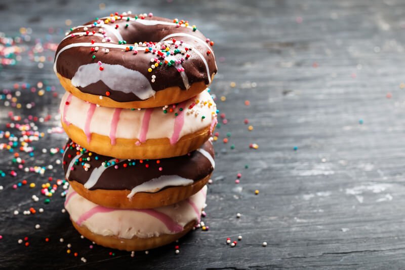 three donuts stacked with sprinkles and icing