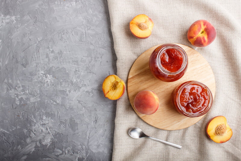 two jars of apricot jam next to whole apricots