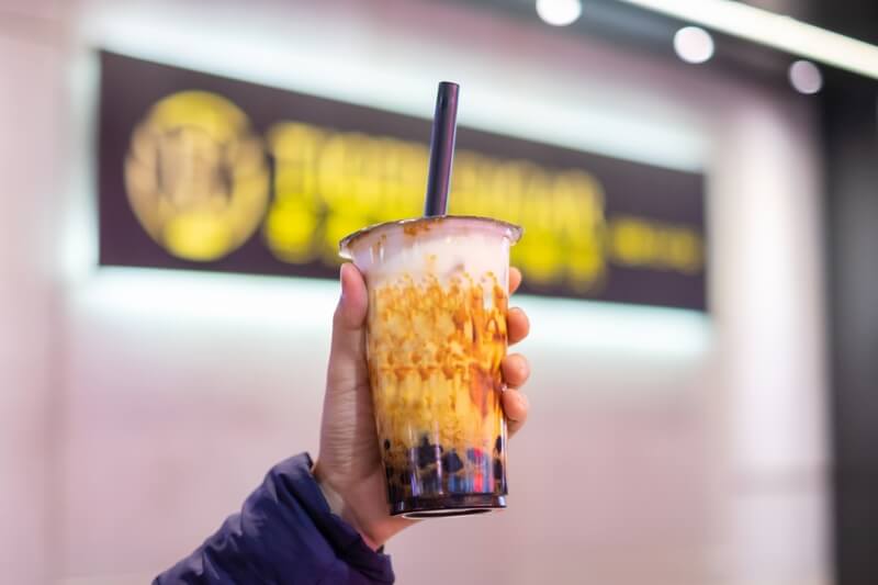 woman holding bubble tea cup in hand with blurry background