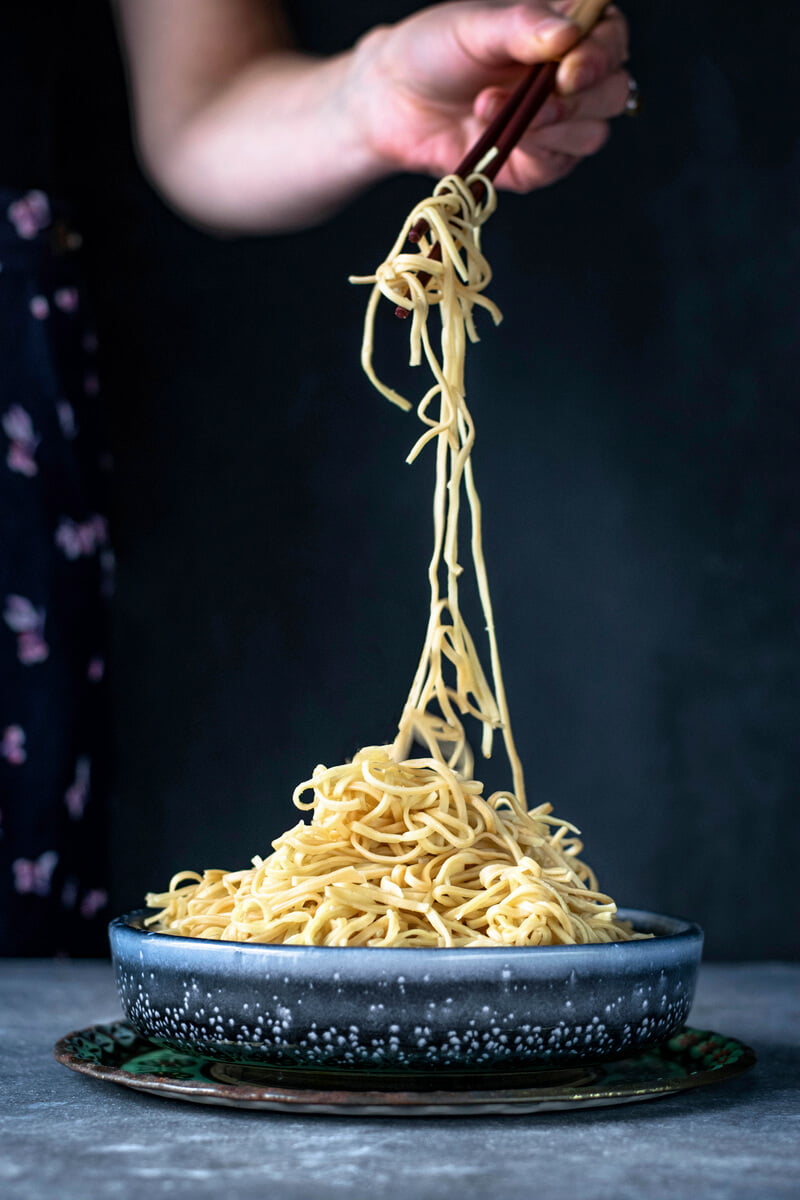 woman twirling egg noodles with chopsticks