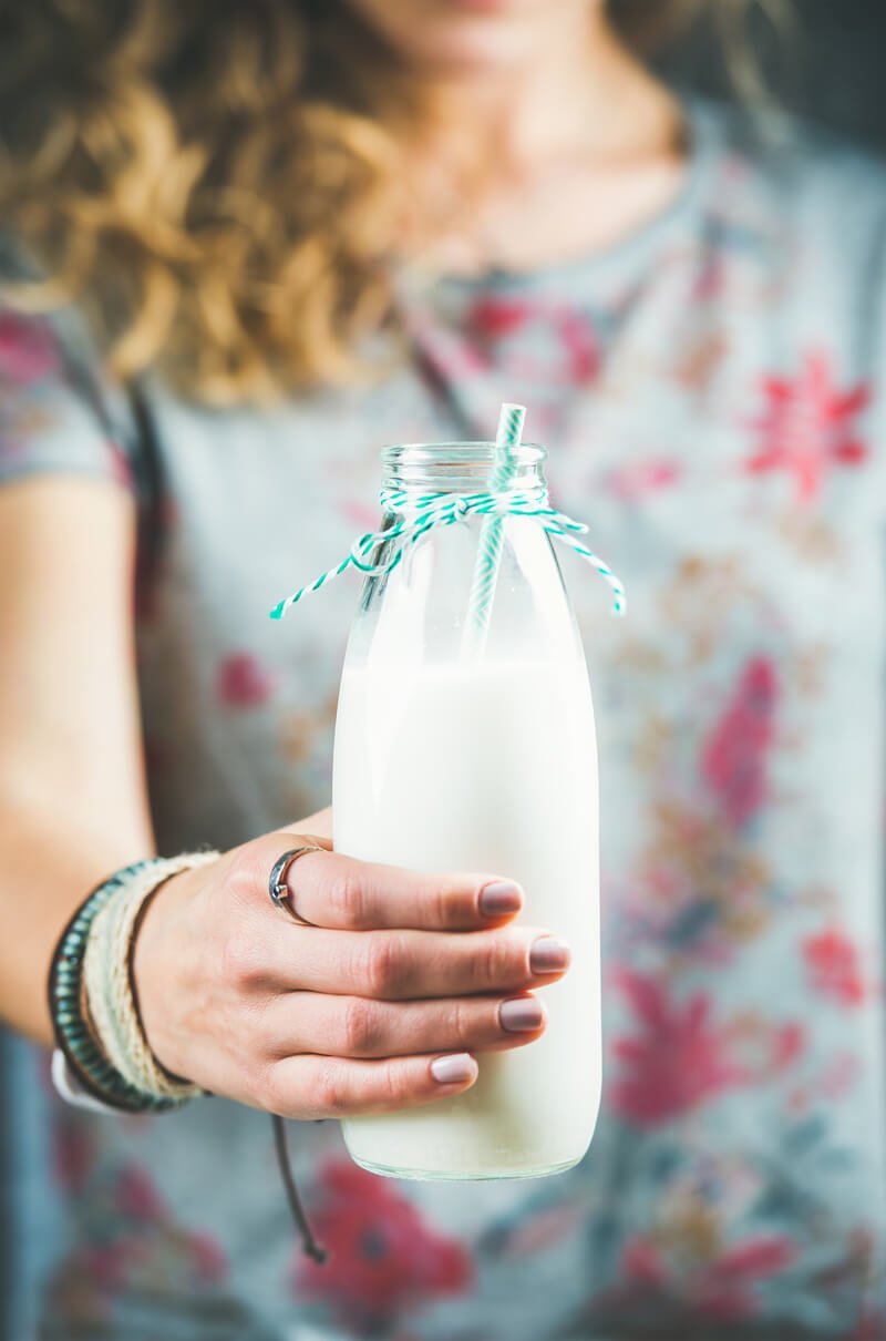 young woman holding bottle of non dairy milk