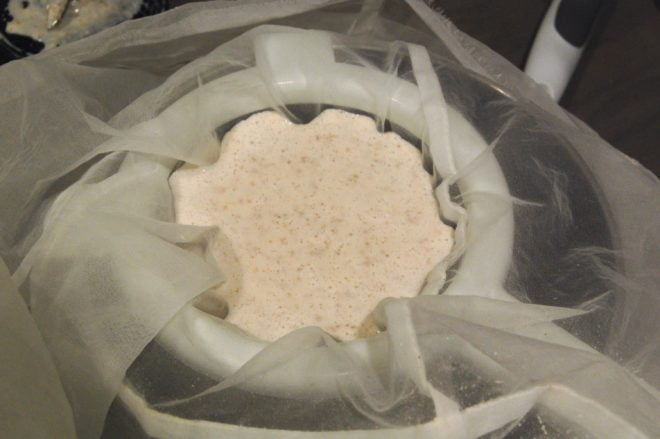 almond milk mixture being strained through nut bag
