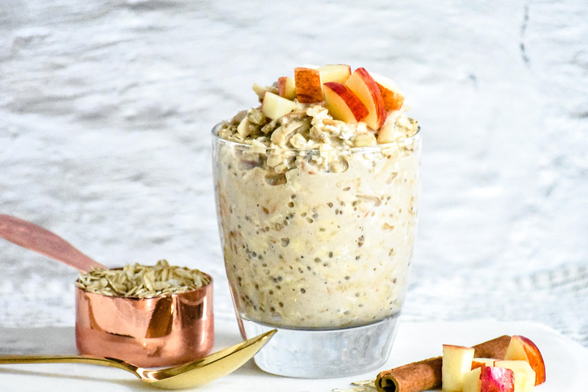 almond milk overnight oats in glass with apples and oats in background