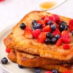 pouring syrup on almond milk french toast topped with berries