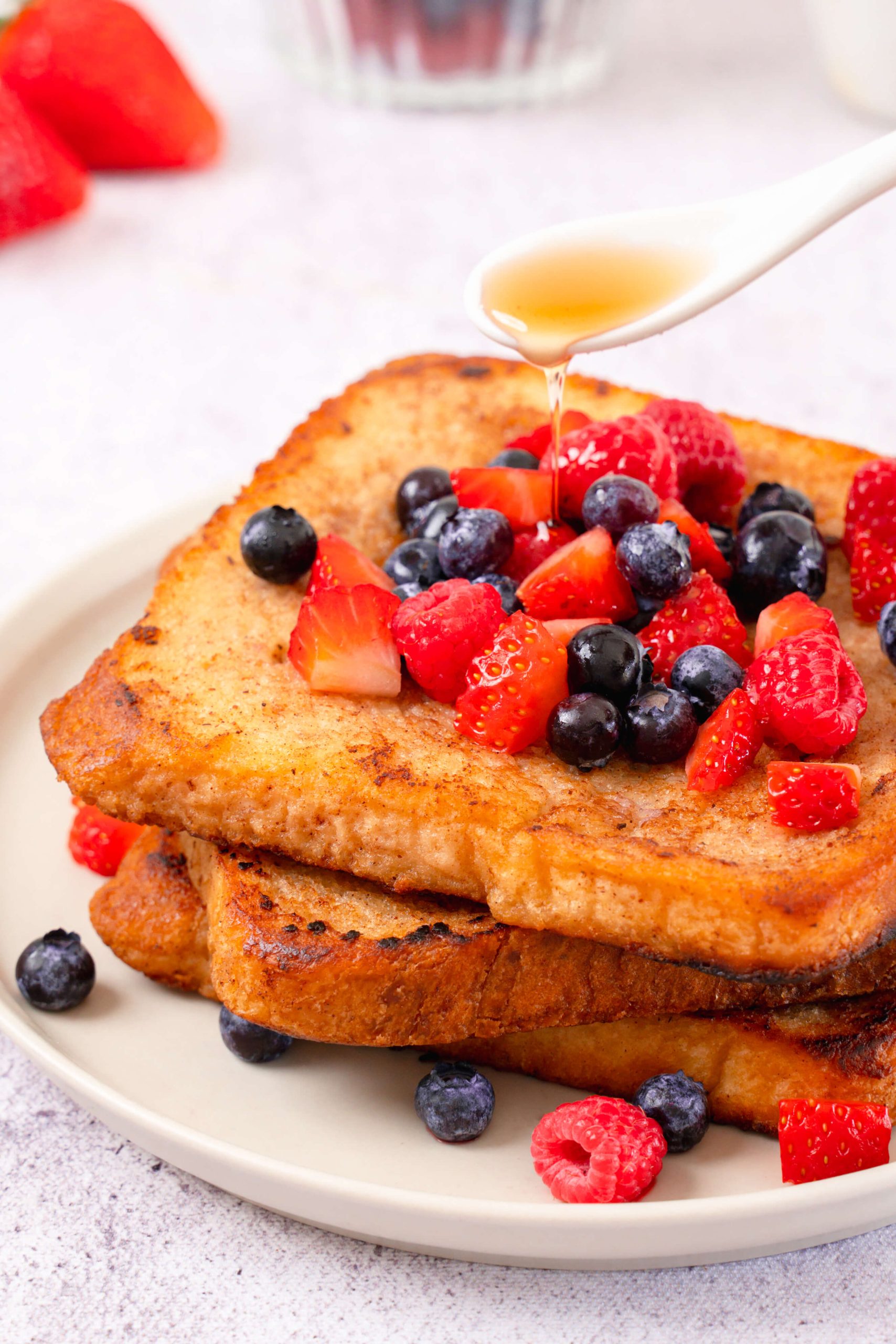 pouring syrup on almond milk french toast topped with berries