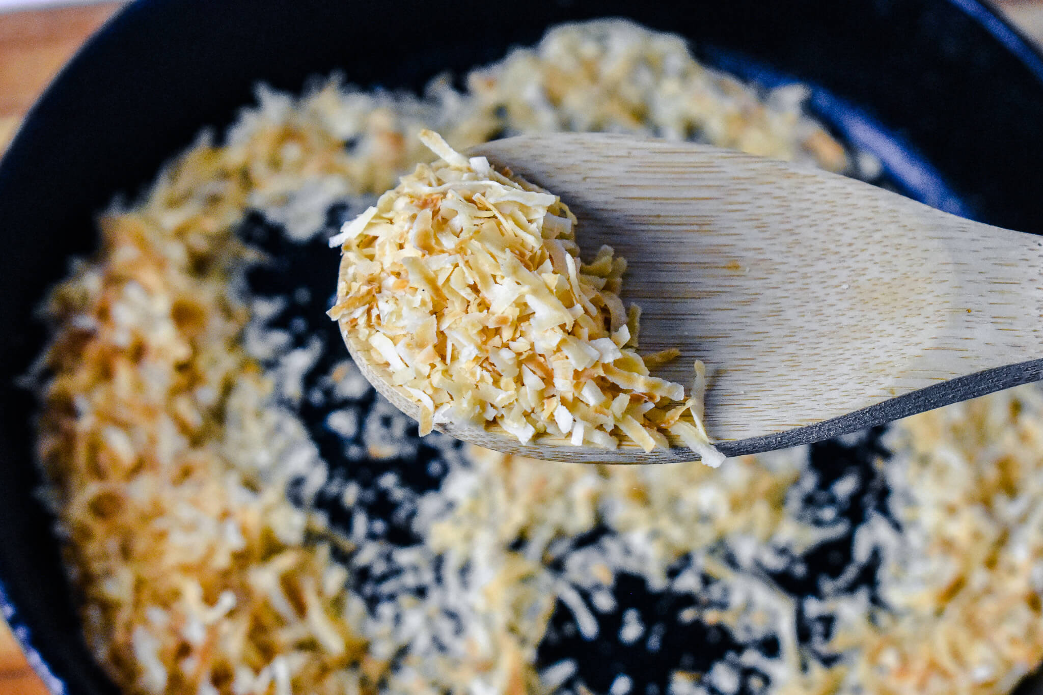 toasted coconut flakes on wooden spoon