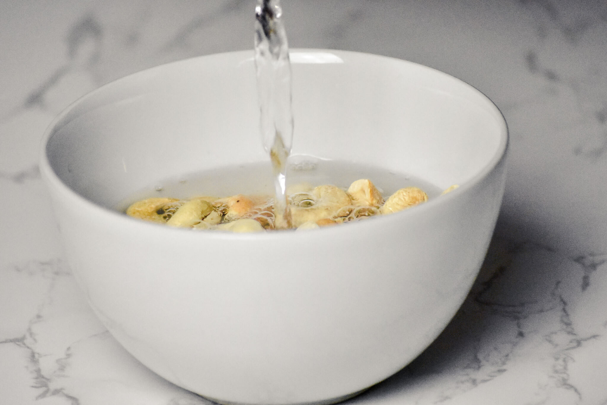 water pouring into bowl of almonds