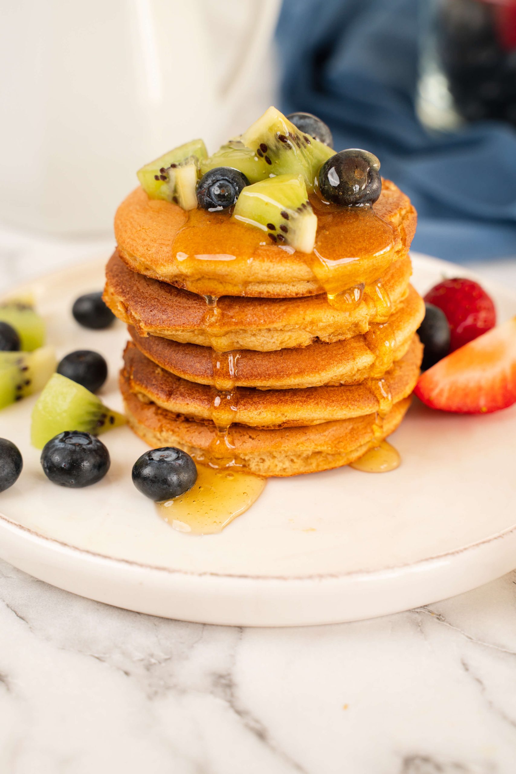 almond milk pancakes topped with blueberries and kiwi with syrup drizzle