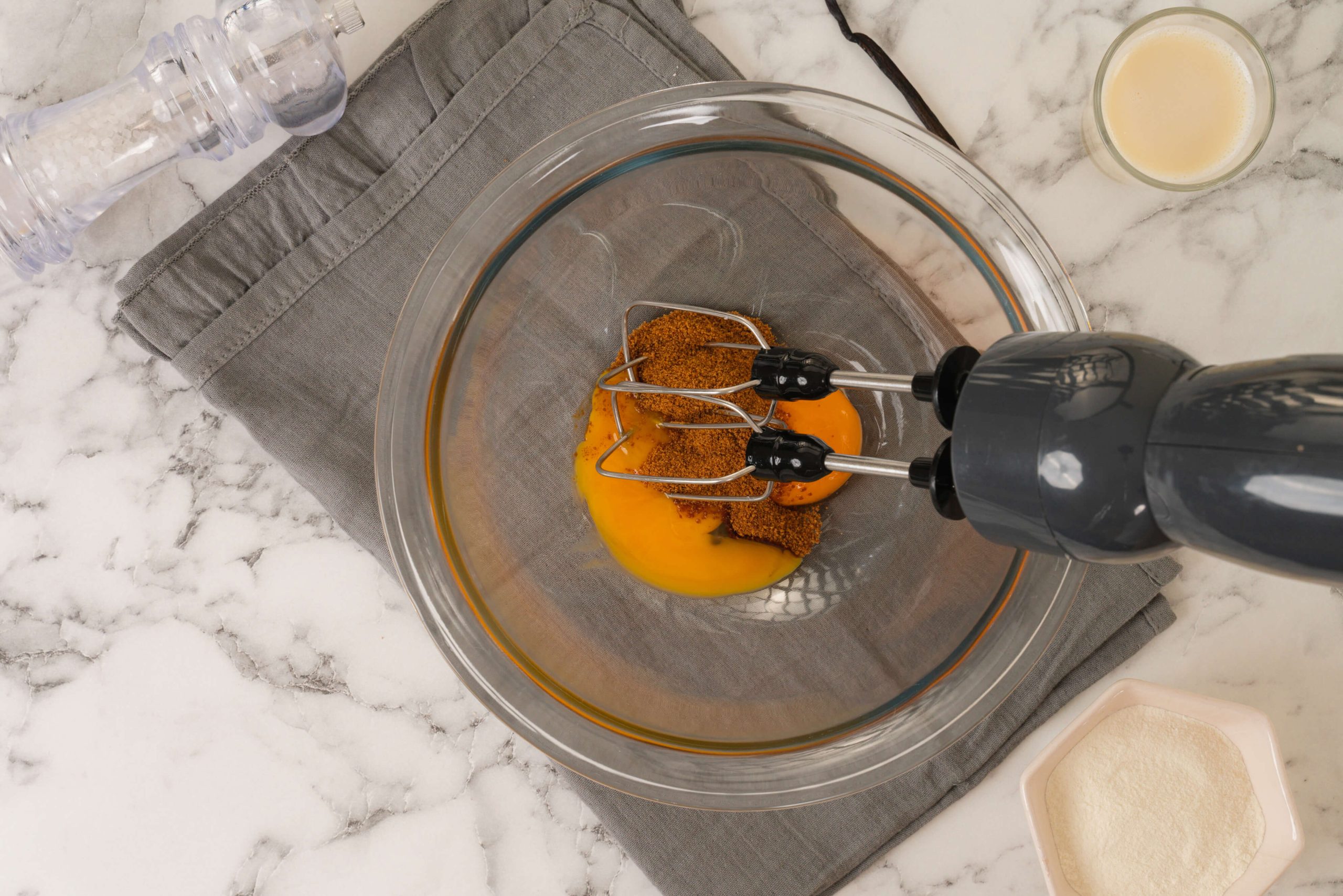 mixing egg yolks coconut sugar vanilla bean and almond milk