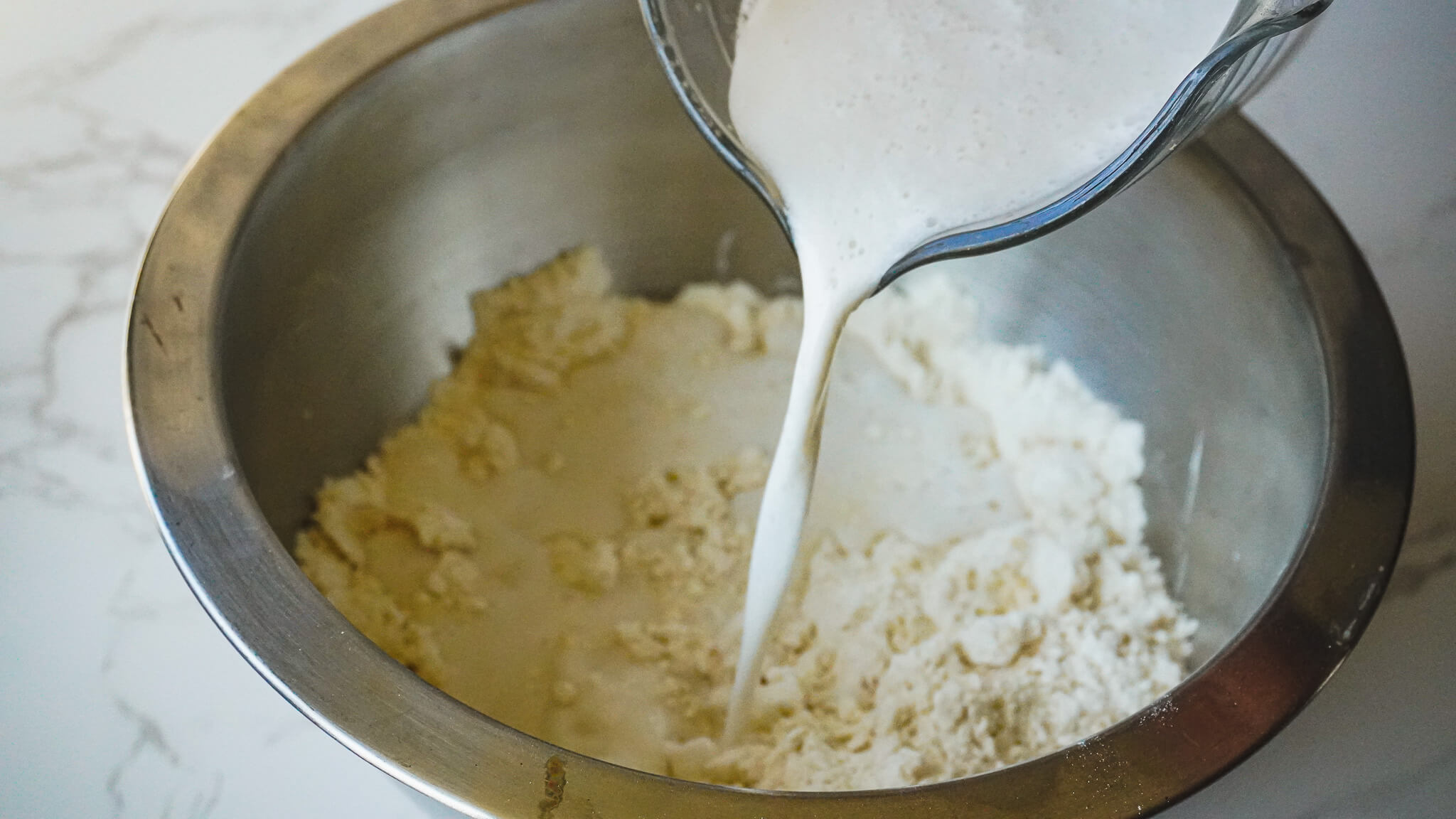 pouring vegan buttermilk into almond milk biscuit dough