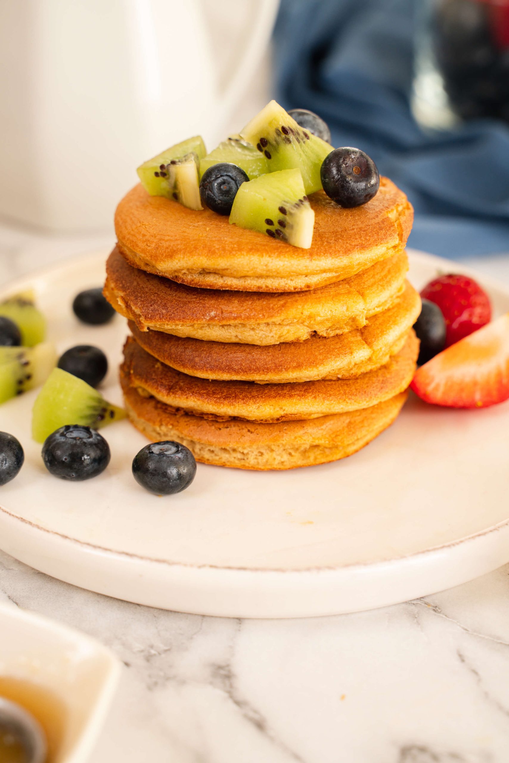 stack of almond milk pancakes topped with fruit on plate