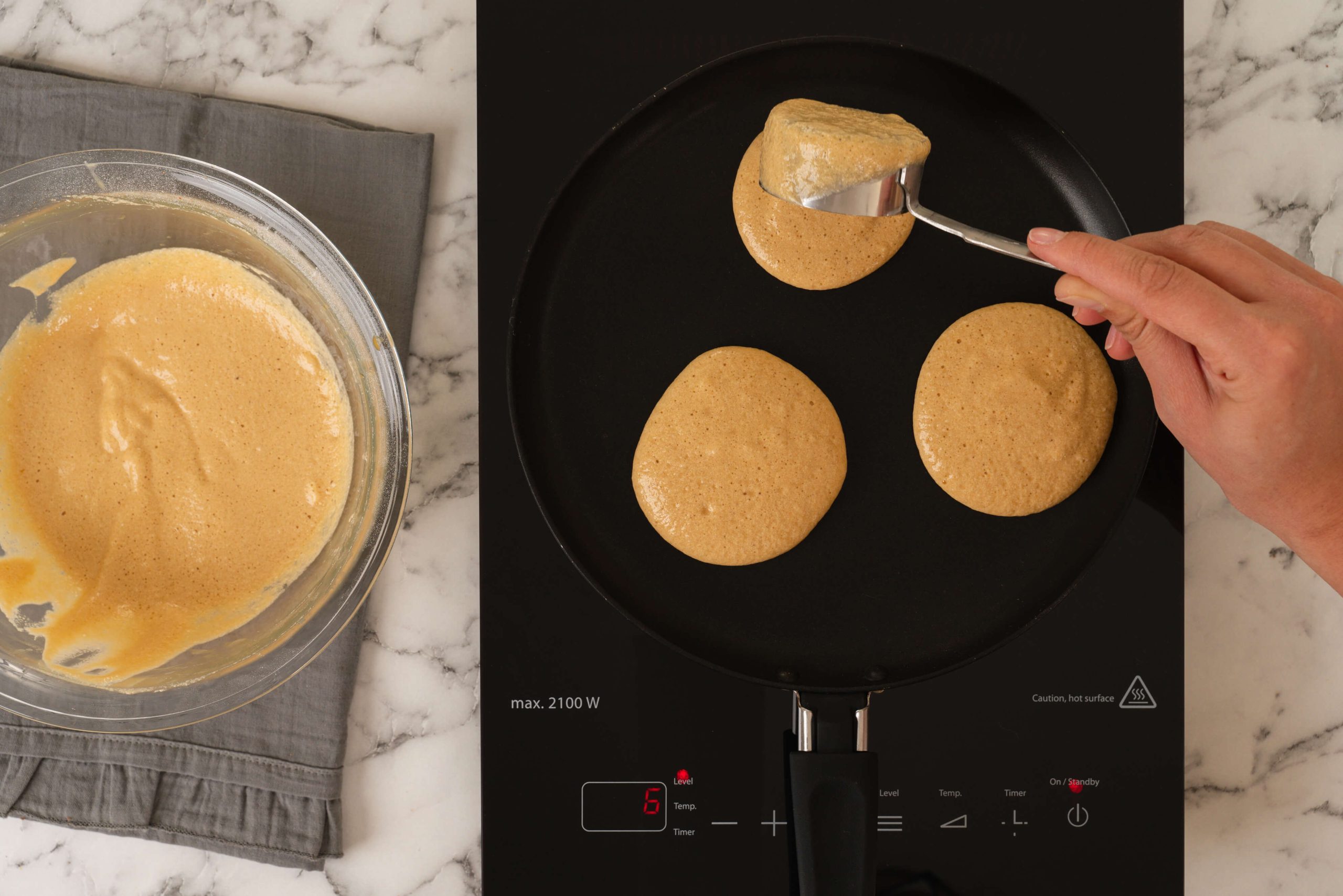 three almond milk pancakes cooking on pan