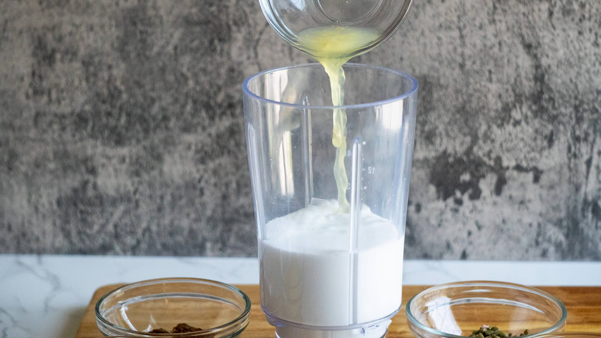 pouring lime juice in dairy-free caesar dressing