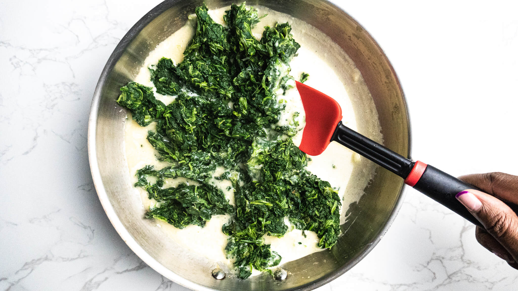 stirring spinach in cream sauce