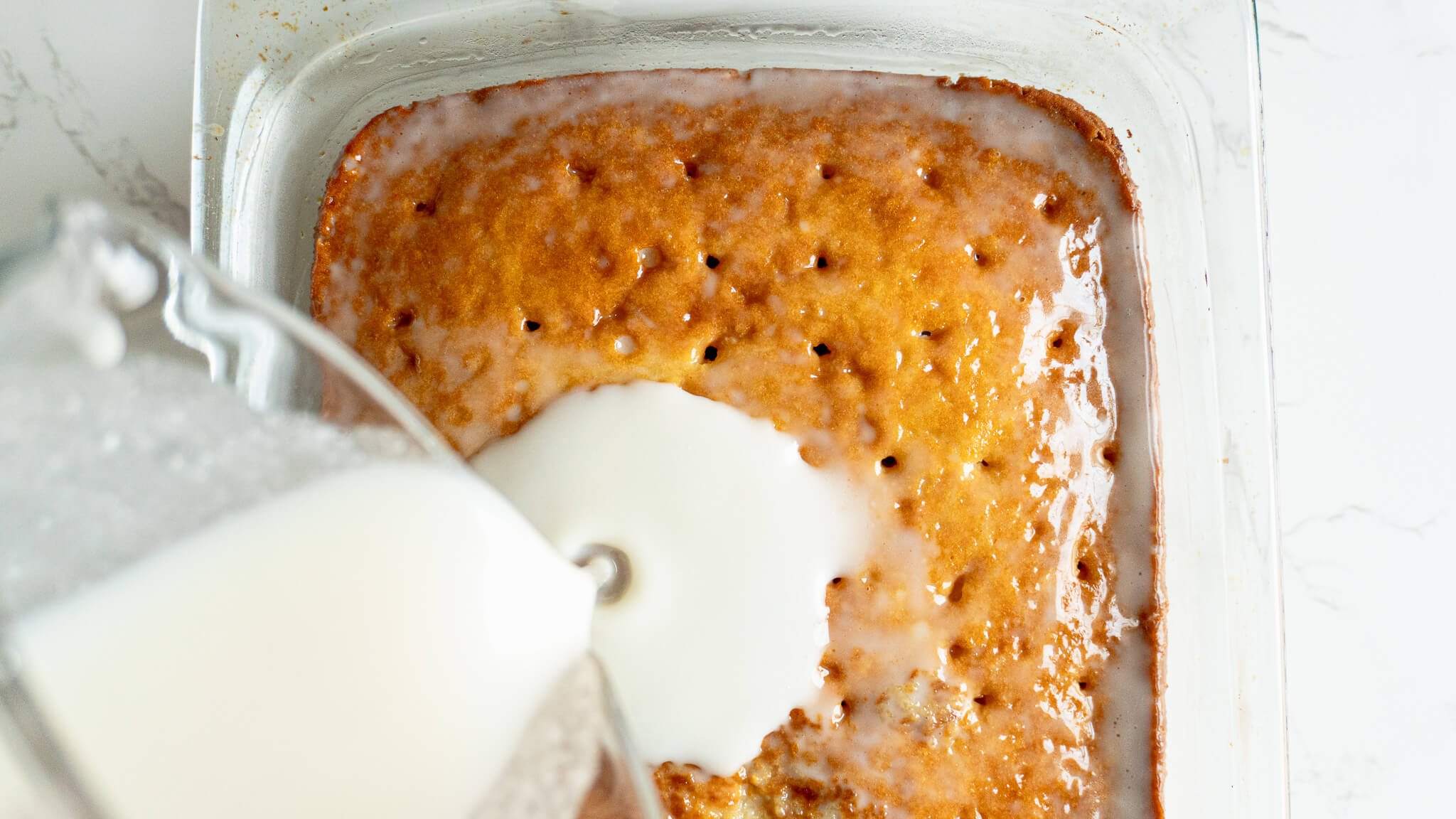 pouring milk over dairy-free tres leches cake
