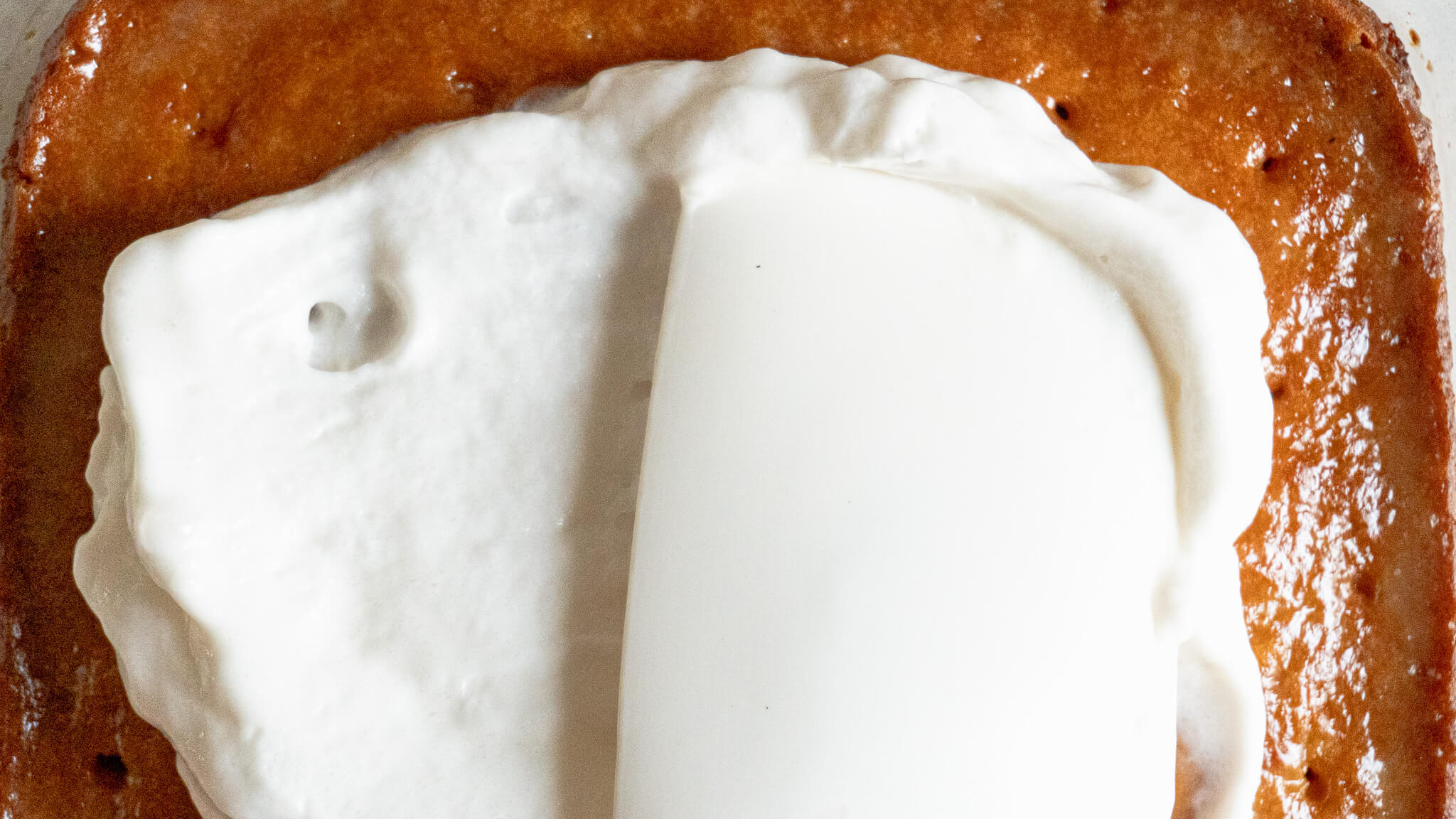 spreading whipped cream on dairy-free tres leches cake